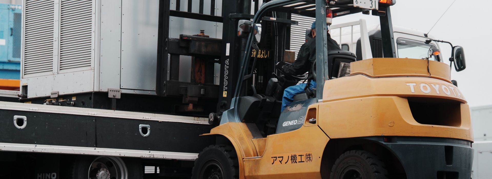 フォークリフトに乗って、機械を運んでいる男性